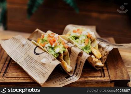 Chicken tacos with guacamole and vegetables on wooden table