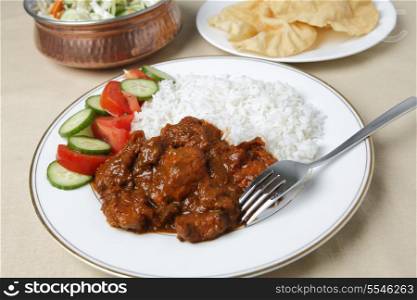 Chicken tikka masala with basmati rice, a salad and poppadums