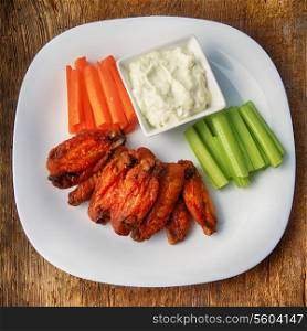 chicken wings with celery and carrot on wooden background
