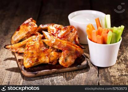 chicken wings with fresh vegetables and sauce on wooden table