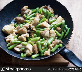 chicken with green beans in fried pan