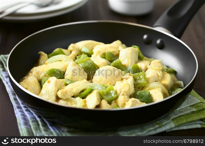 Chicken with green bell pepper and onion in mustard cream sauce in frying pan, photographed with natural light (Selective Focus, Focus in the middle of the dish in the pan)