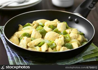 Chicken with green bell pepper and onion in mustard cream sauce in frying pan, photographed with natural light (Selective Focus, Focus in the middle of the dish in the pan)