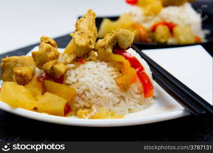 chicken with pineapple and garnished with rice on white and black plates.