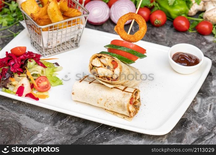 Chicken wrap with french fries and salad on marble table