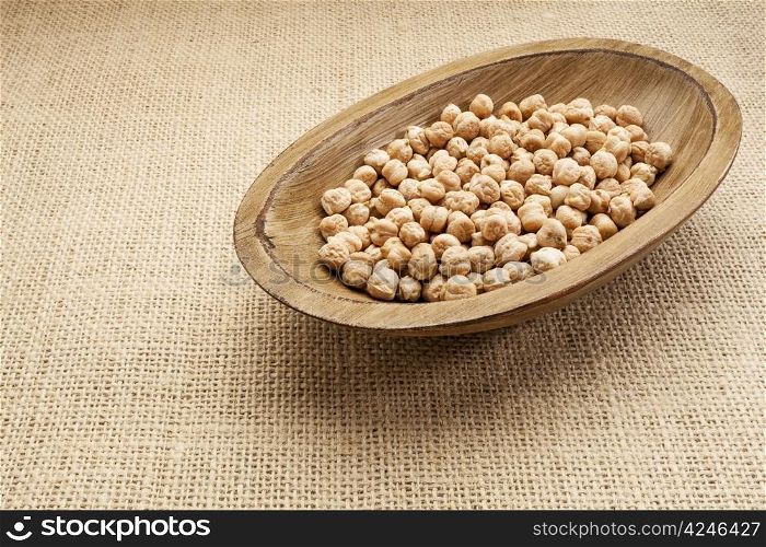 chickpea (garbanzo) beans in a rustic wood bowl against burlap canvas