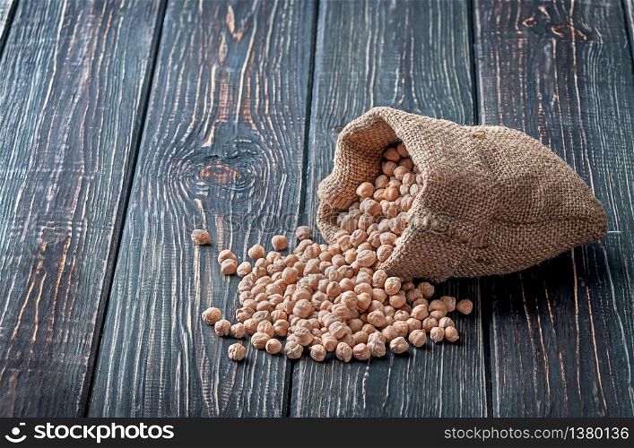 Chickpea spill out of the bag on wooden background. Chickpea spill out of the bag