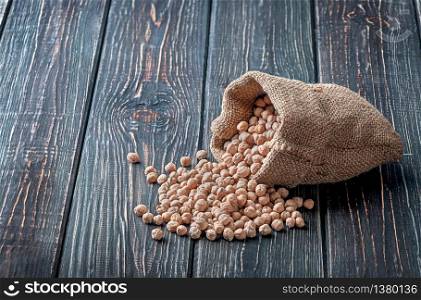 Chickpea spill out of the bag on wooden background. Chickpea spill out of the bag