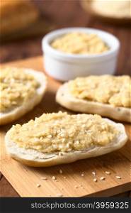 Chickpea spread or hummus on bread sprinkled with sesame seeds, photographed with natural light (Selective Focus, Focus one third into the image)