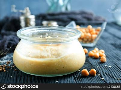 Chickpea spread or hummus with sesame seeds in glass bowl