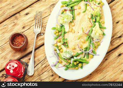 Chickpeas hummus with cabbage,asparagus and peas.Hummus with vegetables on plate. Hummus and variety of vegetable