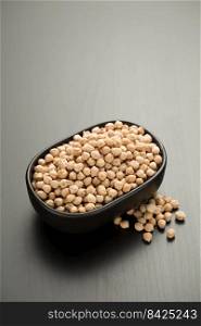 Chickpeas in a small black bowl on a black wooden table.