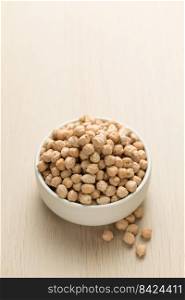 Chickpeas in a small white bowl on a wooden table.