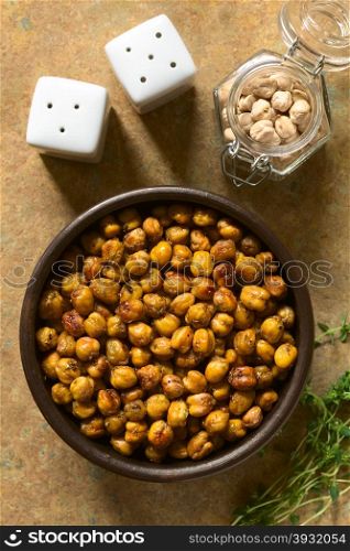 Chickpeas roasted with thyme, oregano, salt and pepper, photographed overhead on slate with natural light (Selective Focus, Focus on the chickpeas)