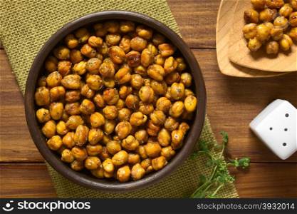 Chickpeas roasted with thyme, oregano, salt and pepper, photographed overhead on wood with natural light (Selective Focus, Focus on the chickpeas)