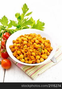 Chickpeas stewed with celery, tomatoes, onions, carrots and garlic in a plate on a towel on white wooden board background