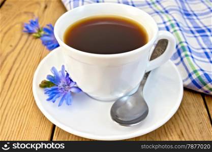 Chicory drink in a white cup with a flower on a saucer and spoon, napkin on wooden board