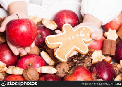 Child&#39;s hands hold a red apple and gingerman cookie