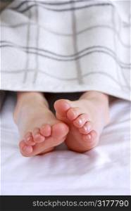 Child&acute;s feet sticking out of a blanket in a bed