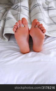 Child&acute;s feet sticking out of a blanket in a bed