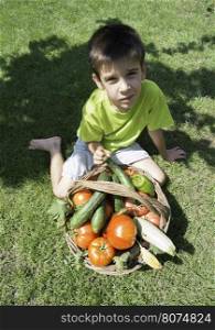 Child and basket with vegetables. Green meadow
