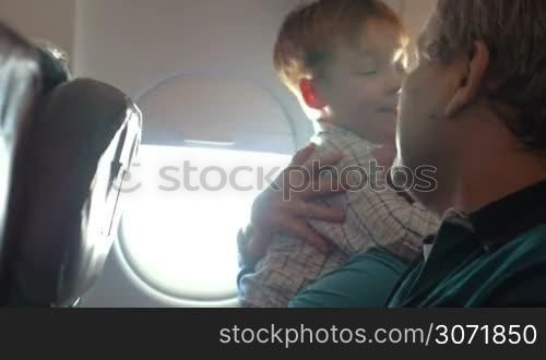 Child and grandparents in the plane. Happy boy and grandmother hugging, grandfather sitting nearby