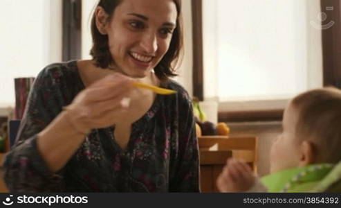 Child and nutrition, mom feeding little baby girl with homogenized food in home kitchen for lunch. Sequence