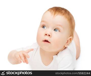 child and toddler concept - curious baby lying on floor and looking side