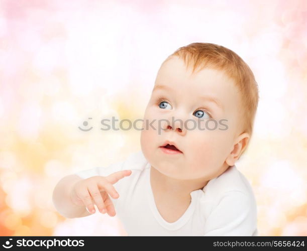 child and toddler concept - curious baby lying on floor and looking side