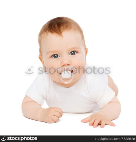 child and toddler concept - smiling baby lying on floor with dummy in mouth