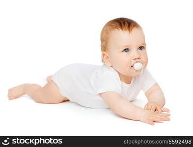 child and toddler concept - smiling baby lying on floor with dummy in mouth