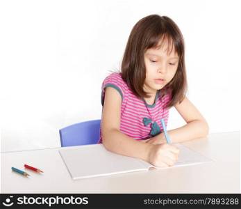 Child at desk with pencils and notebook