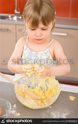 Child baking - little girl kneading dough in kitchen