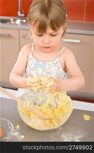 Child baking - little girl kneading dough in kitchen