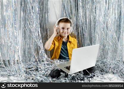 child boy in headphones with laptop on party background. Kids lightening music. Electronic device for learning, studying or having fun. Gadget and screen time for children.. child boy in headphones with laptop on party background. Kids lightening music. Electronic device for learning, studying or having fun. Gadget and screen time for children