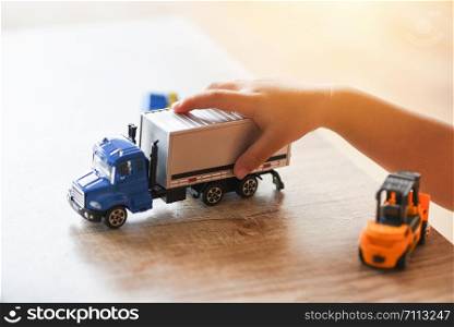 child boy playing toys on table at home / kid hands playing toy car truck