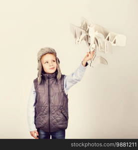 Child boy playing with paper toy airplane and dreaming of becoming a pilot. Retro toning.