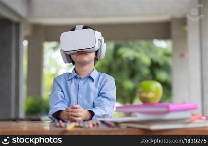 Child boy wears VR glasses (Virtual reality glasses). He is surprised by the content shown before his eyes by smarthphone in side connect by application.3D gadget technology.