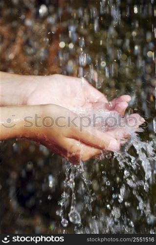 Child catching falling water with her hands. Environmental concept.