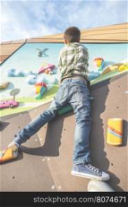 Child climb a climbing wall. Playground