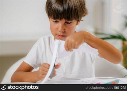 Child cutting cards with shapes in a preschool assessment test.