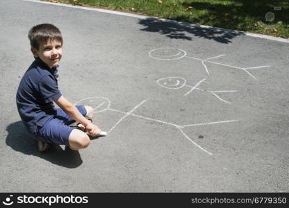 Child drawing family on asphalt in a park