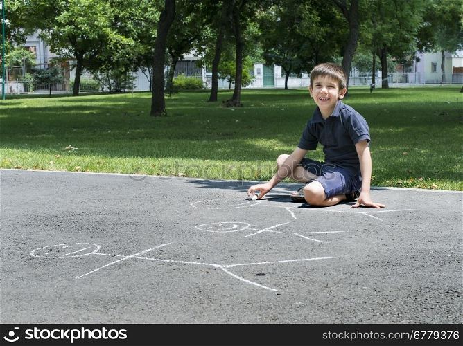 Child drawing family on asphalt in a park