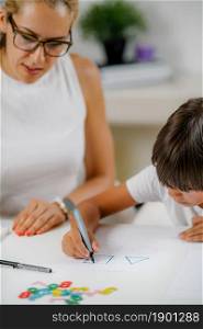 Child drawing shapes in a preschooler assessment test. Psychologist helping him.. Child drawing shapes in a preschooler assessment test.