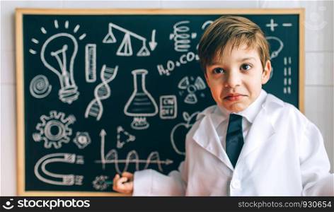 Child dressed as a scientist in front of chalkboard with drawings