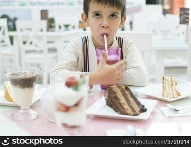Child drink lemonade. Cake and a milkshake in confectionery.