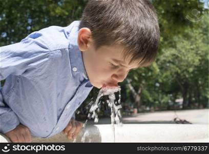 Child drinking water from a fountain. Close up