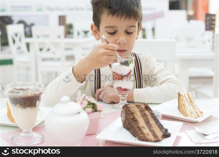 Child eat strawberry smoothie. Choco Cake on a table