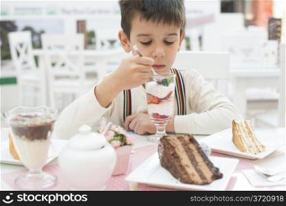 Child eat strawberry smoothie. Choco Cake on a table