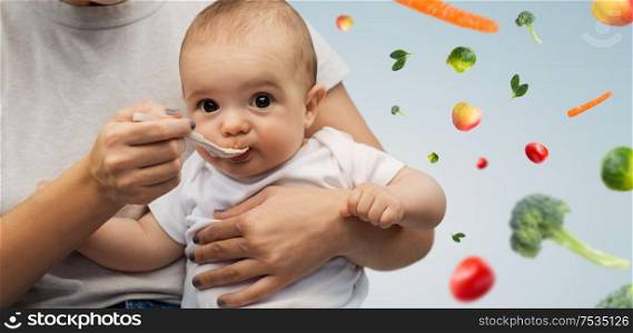 child, eating and food concept - close up of mother with spoon feeding little baby over fruits and vegetables on background. close up of mother with spoon feeding little baby